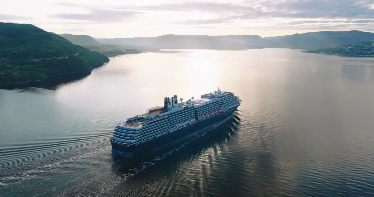 Cruise ship sailing into golden-hour fjord light in the Bay of Islands